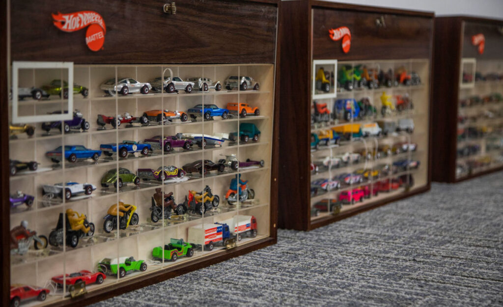 Exposição de Hot Wheels raros e personalizados em um evento de colecionadores, com diversos modelos em destaque.